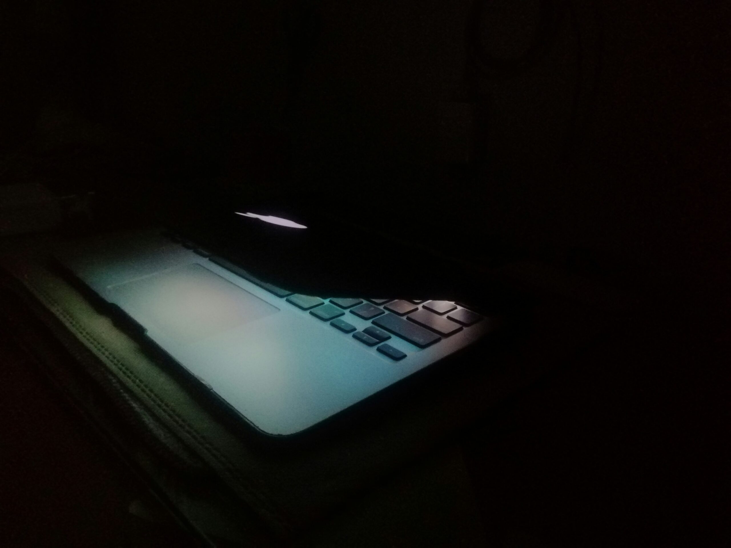 Sad teenager on laptop in dark room - a laptop computer lit up in the dark